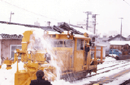 線路の雪を流雪溝に投げ込むロータリー除雪車
